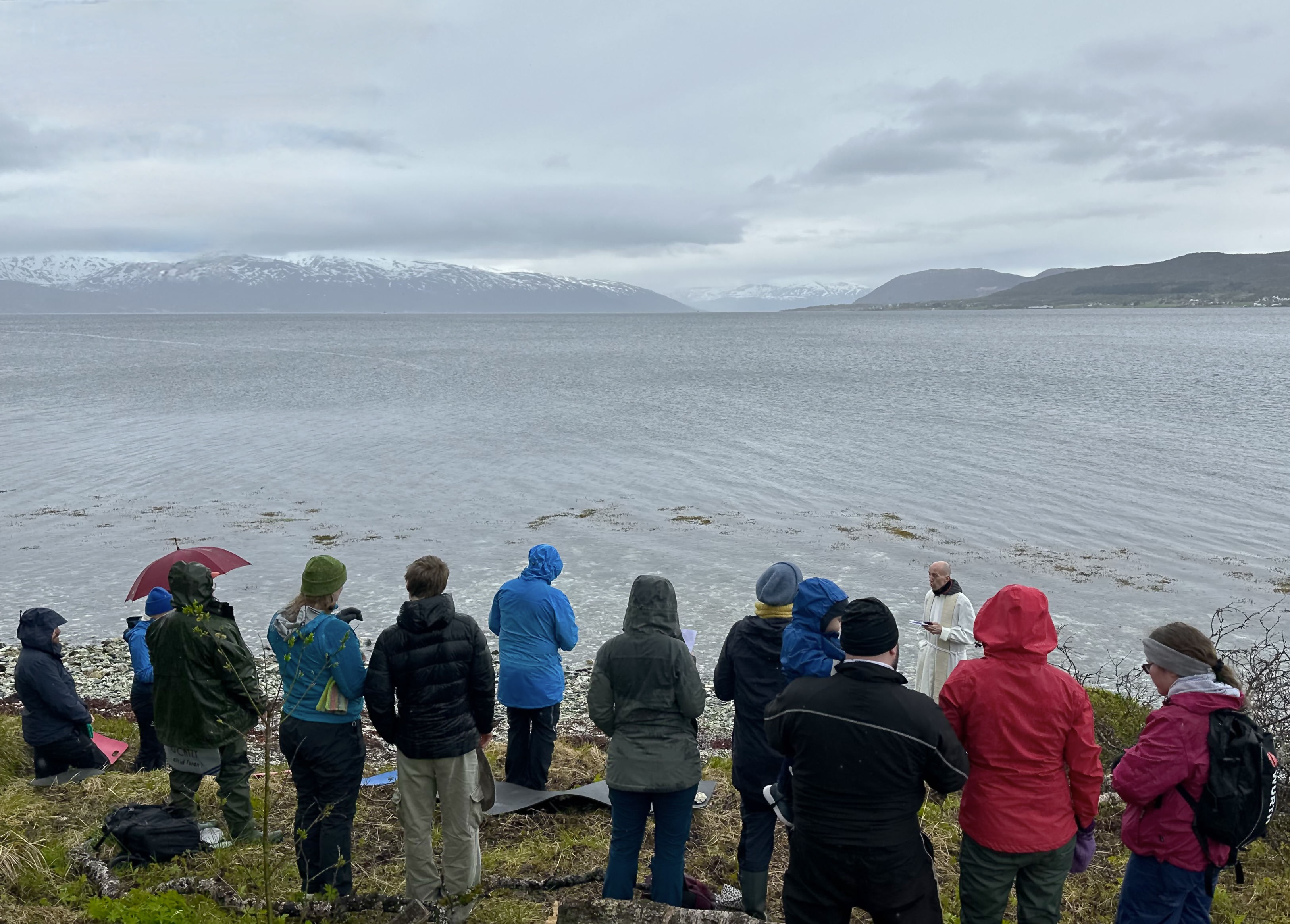 Människor på stranden. Berg och hav i bakgrunden.