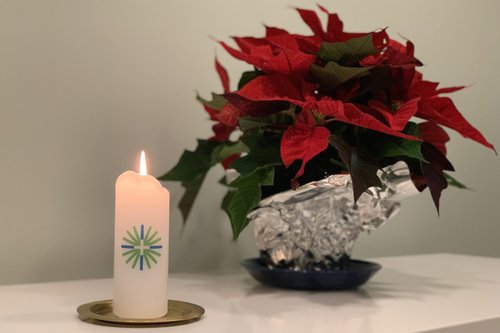 Ett brännande ljus med församlingens logo och en röd julstjärna på kansliets bord i Oslo.