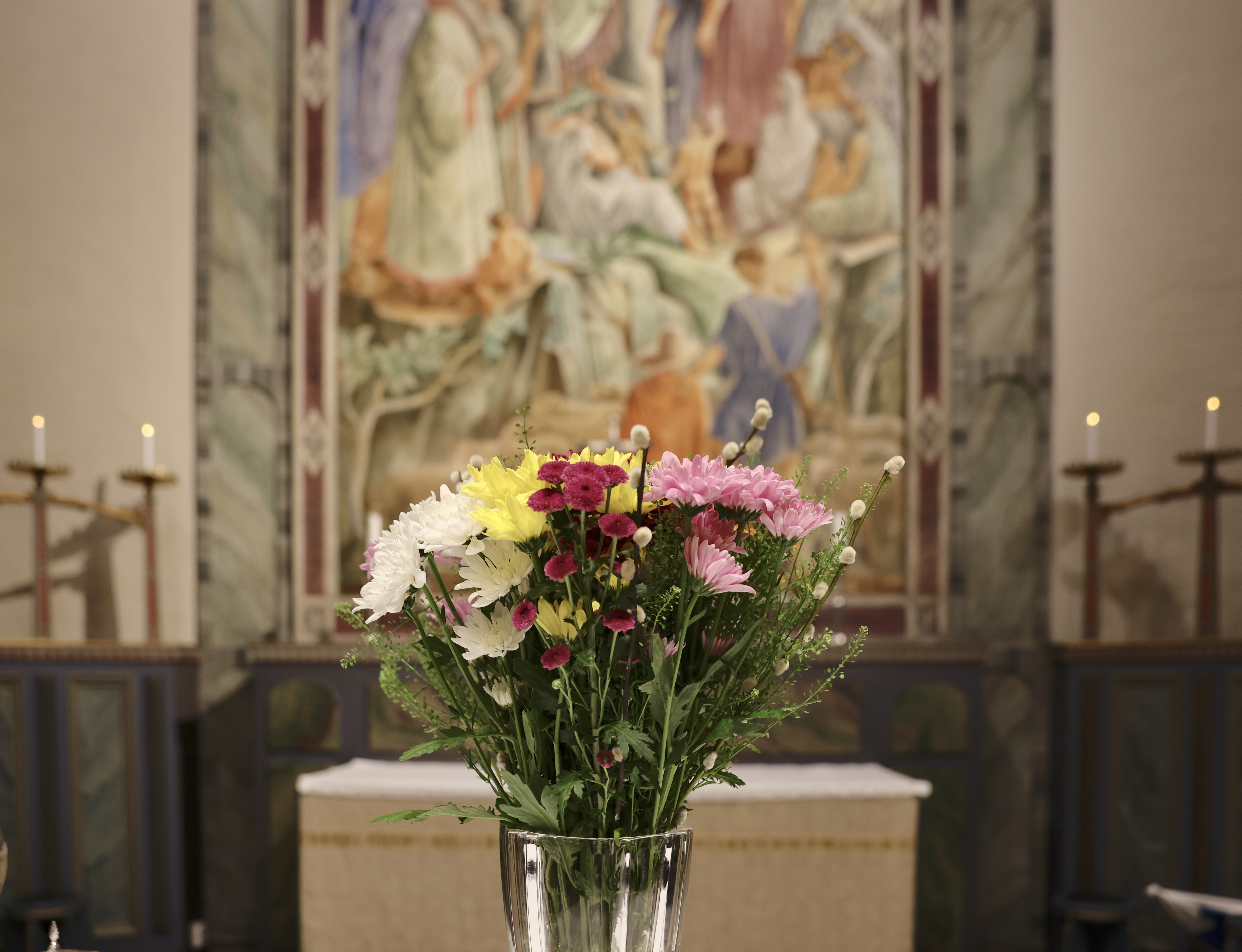 Blomsterarrangemang på altaret i kyrkan.