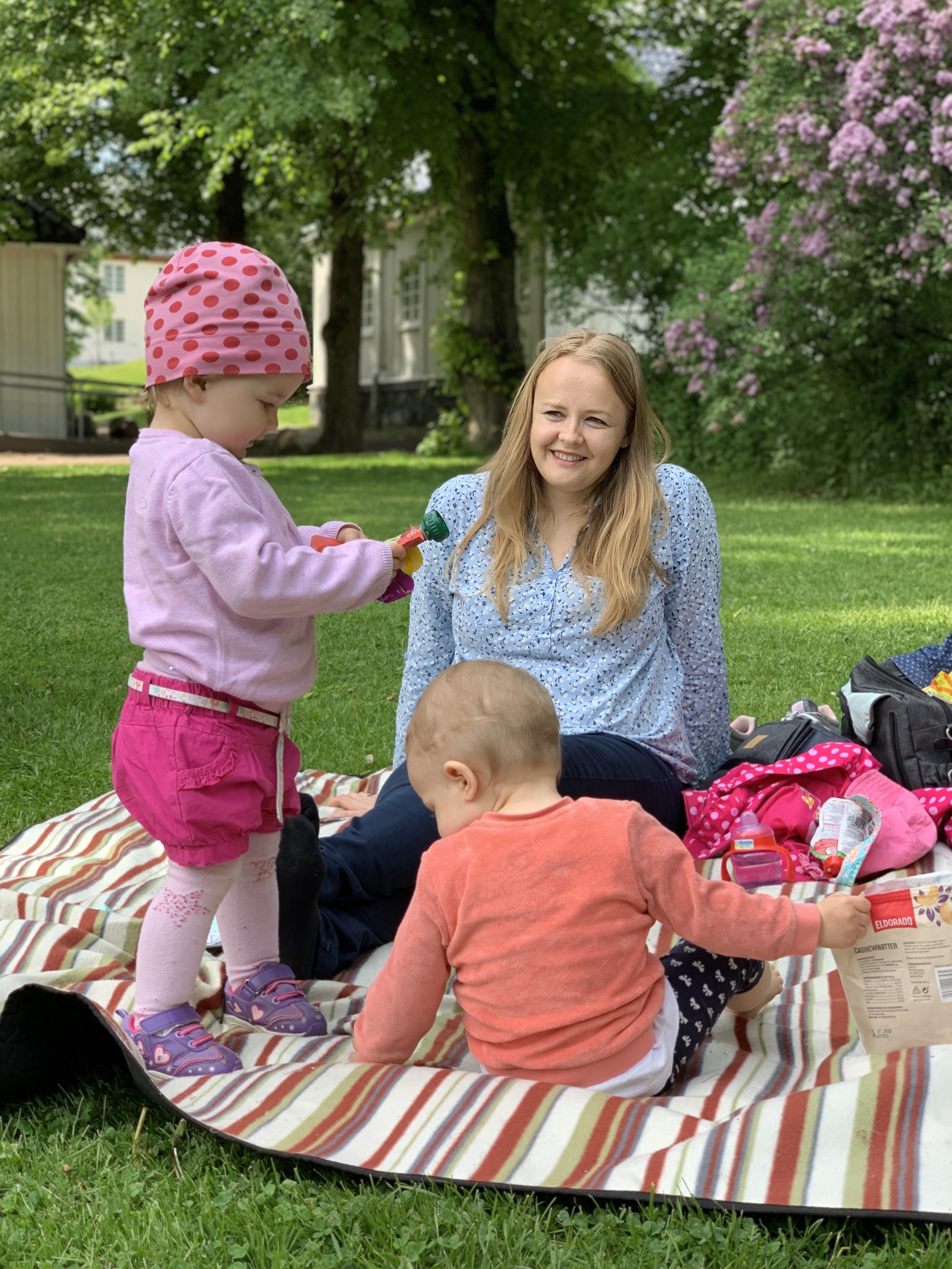 Oslo: Babycafé ute i gräset Mor och två små barn som leker på filten i gräset.