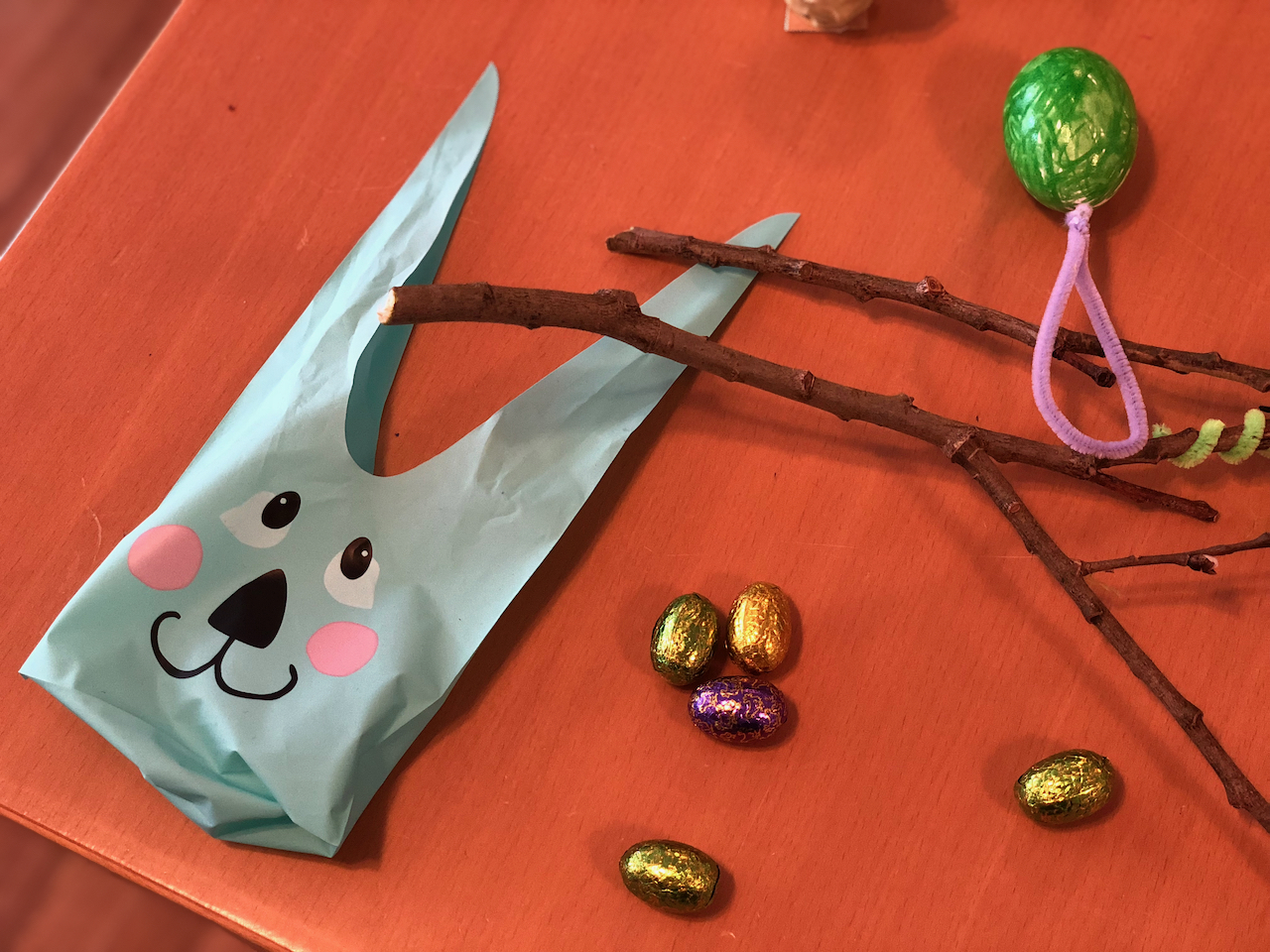 På bordet finns en påse med ett ansikte av en hare och små chokladägg inlindade i papper.
